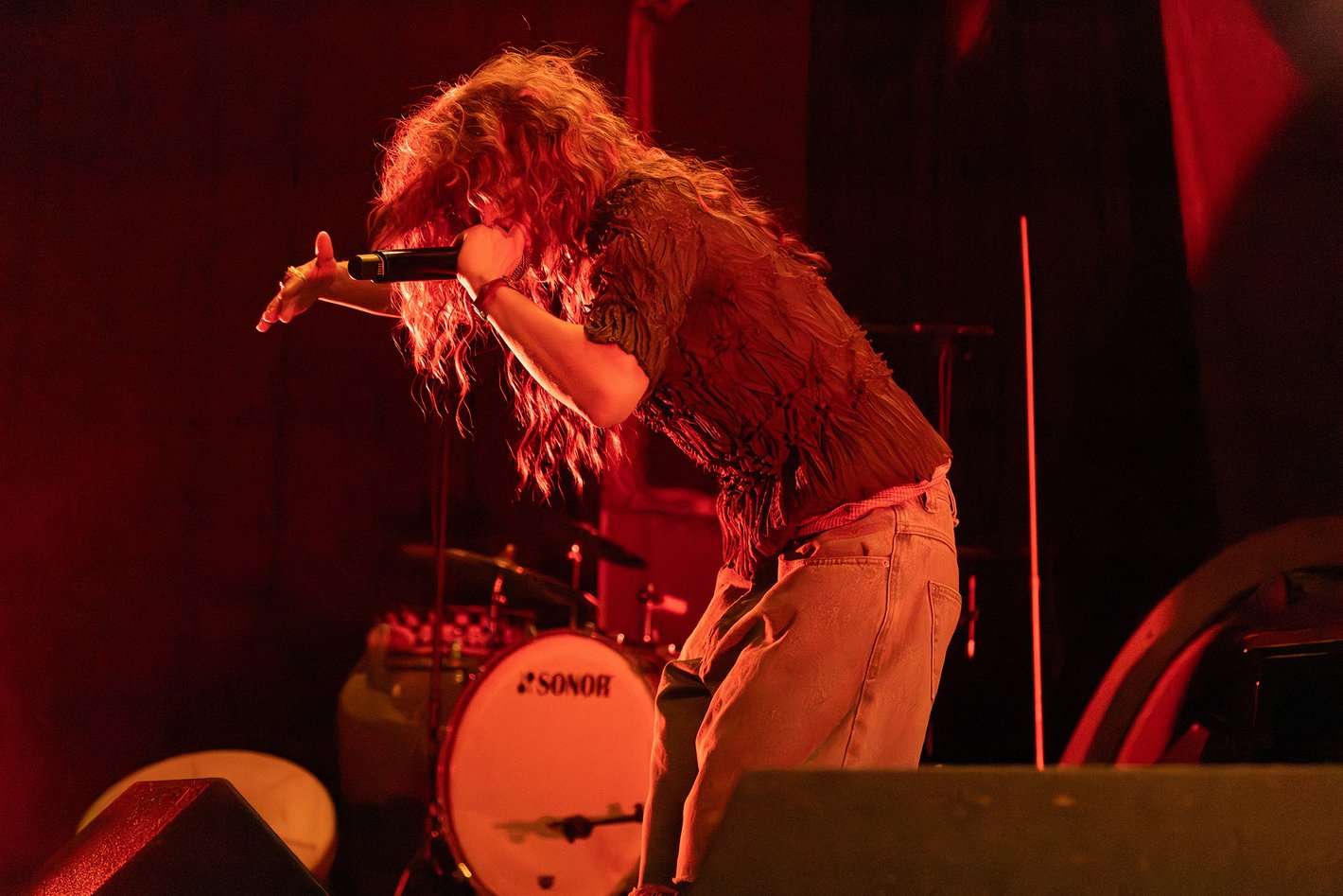 Eine Frau mit Mikrofon im roten Licht auf der Bühne.