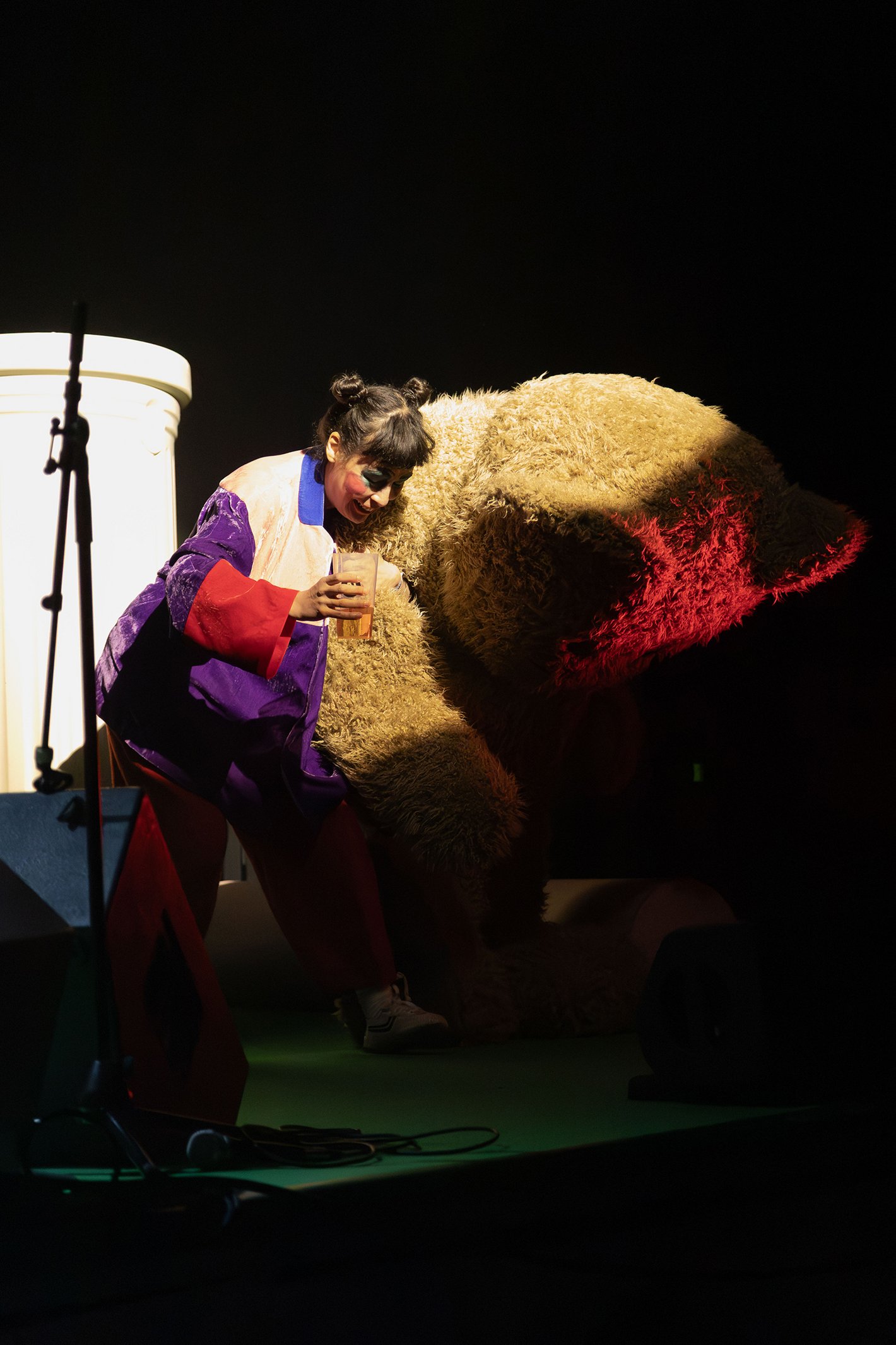 Eine Frau in bunter Kleidung neben einem übergroßen Plüschbär.