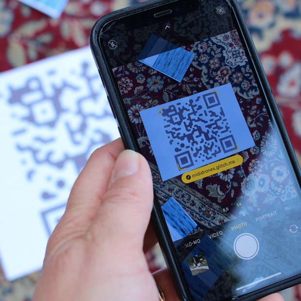 Hand die mit einem Handy einen QR-Code scannt.